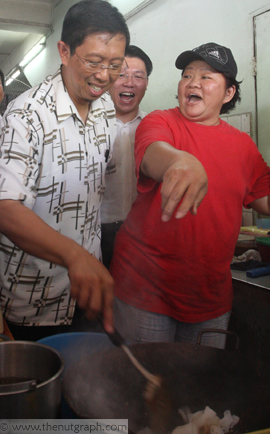 Nizar frying char kuey teow while happy hawker watches