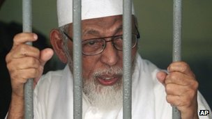 Radical cleric Abu Bakar Ba'asyir talks to reporters from behind bars of a holding cell at a district court in Jakarta, Indonesia, on 9 May 2011 