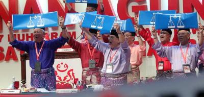 <b>Show of strength:</b> Najib and other party leaders holding Barisan flags while singing the BN anthem at the Umno General Assembly in PWTC.