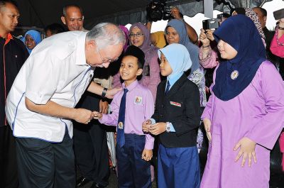 Close attention: Najib speaking with a pupil of SK Sri Wakaf Baru in Tumpat, Kelantan. — Bernama