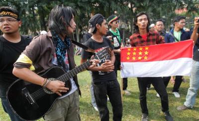 Setting the mood: Student activist Adam Adli (second from left) playing the guitar as rally participants sing along at Padang Merbok.