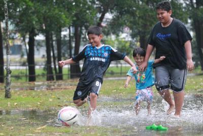 Splashing good time: Children playing football at a playground in Taman Puncak Jalil after the ‘mini rainfall’.
