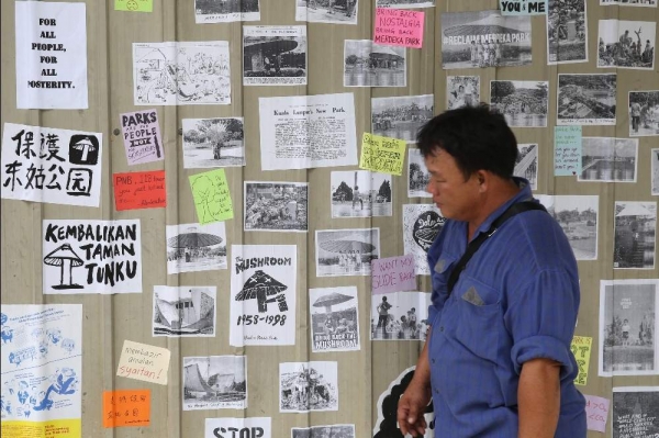 A man looks at the wall plastered with old photographs featuring the mushroom in Tunku Park and also a poster saying ‘Kembalikan Taman Tunku’ (Return Tunku Park). 